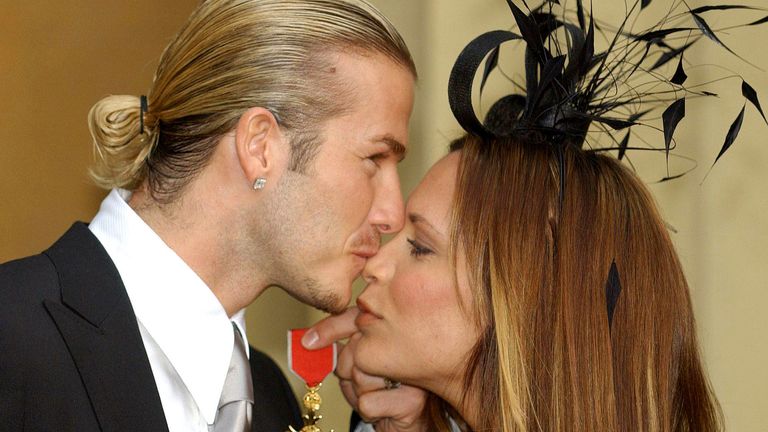 David Beckham isi saruta sotia, Victoria, in timp ce tine OBE Pic:AP